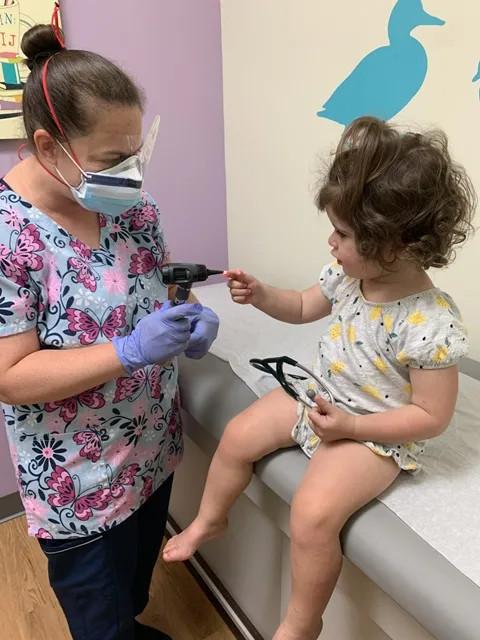 a girl having her finger poked by a medical person