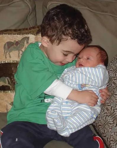 a young boy holding a baby